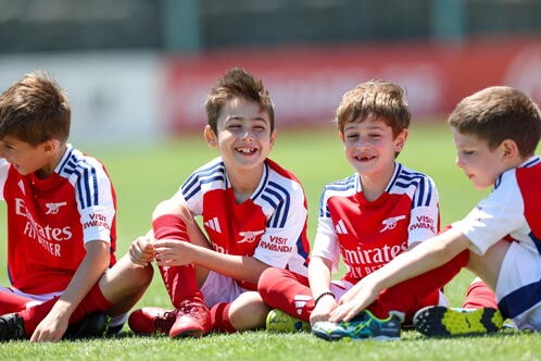 Vier Jungs im Fußballdress auf dem Rasen sitzend