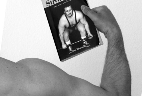 Muskulöser Arm, der das Buch von Doug Hepburn hält
