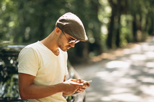 Mann mit Schiebermütze, der sich über sein Handy beugt