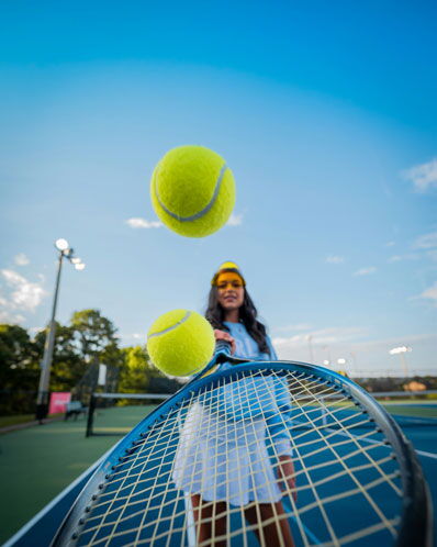 Frau, die zwei Tennisbälle in die Luft wirft