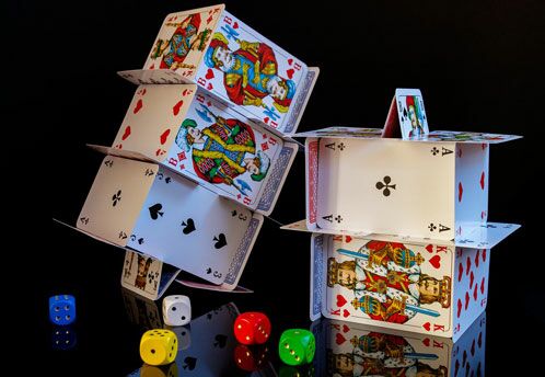 Gestapelte Pokerkarten und Würfel auf schwarzem Hintergrund