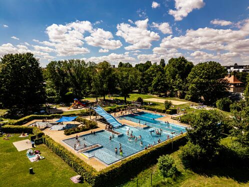 Luftbildaufnahme des Freibad Cotta umrahmt von Bäumen, in der Mitte Badefläche