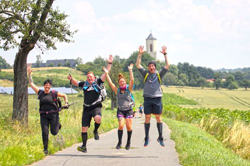4 Wanderer auf einem Weg inmitten von Wiesen