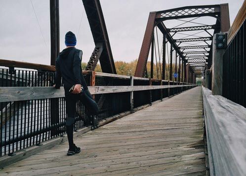 Mann auf einer Brücke, der seine Oberschenkel dehnt