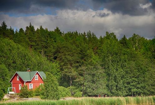 Ein rotes Haus vor grünem Wald in Finnland