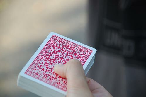 Hand mit einem Kartenspiel mit roter Rückseite