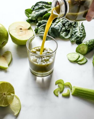 Saftglas, daneben aufgeschnittenes Obst und Gemüse