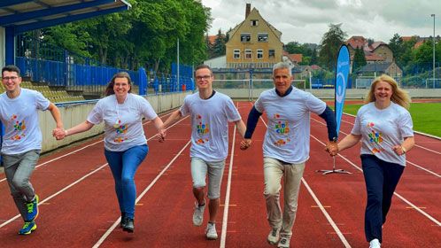 Fünf Personen rennen auf der Tartanbahn