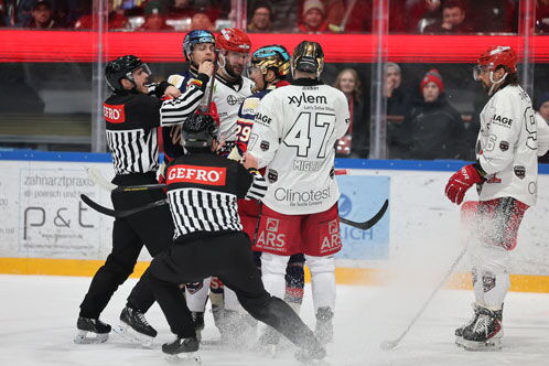 Eishockeyspieler geraten aneinander, werden von zwei Schiedsrichtern getrennt