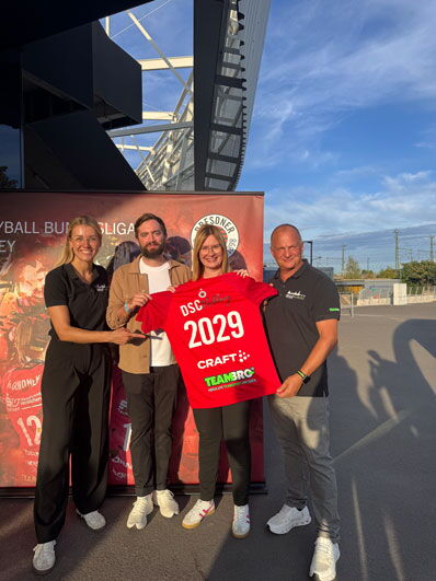 Vier Personen halten ein rotes Fan-Trikot in die Höhe