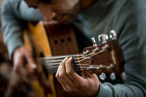 Detailaufnahme eines Mannes beim Gitarrenspiel