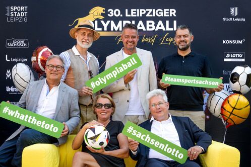 Sponsoren und Verantwortliche des Olympiaballs vor einer schwarzen Wan