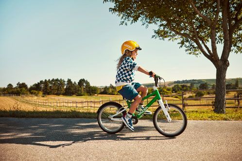 Kind mit gelben Helm auf einem Kinderfahrrad