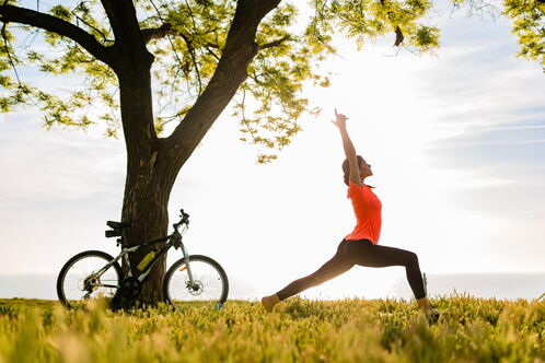 Frau auf einer Wiese in einer Yoga-Pose