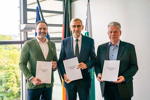 Drei Männer, die weiße Hefter in der Hand halten