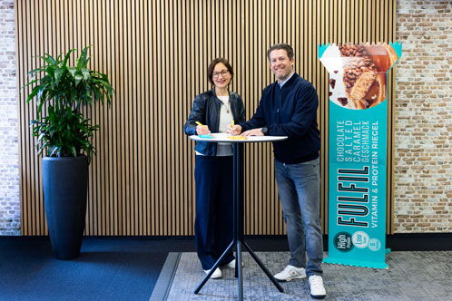 Zwei Personen vor einer Werbetafel der Firma Fulfil