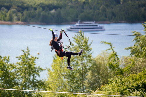 Frau, die an einem Seil im Kletterpark heruntergleitet