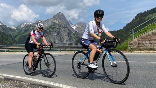 Zwei Frauen fahren auf Rädern einen Pass herauf