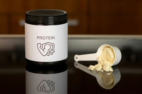 Braune Dose mit Proteinpulver, daneben ein Plastiklöffel