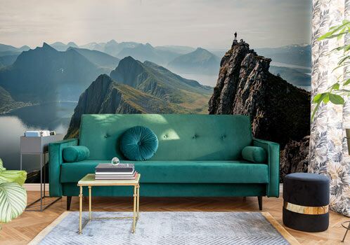 Grünes Sofa vor Tapete mit Bergmotiv