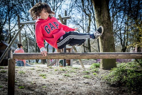 Junge, der über einen Holzbalken springt