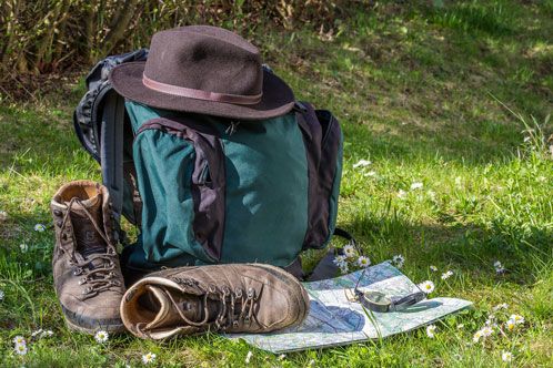 Rucksack und Wanderschuhe auf grüner Wiese