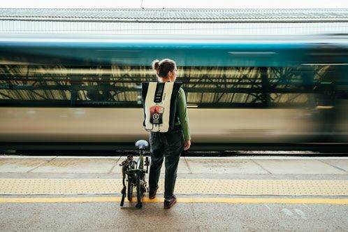 Frau mit Klapprad vor einem Bahnsteig
