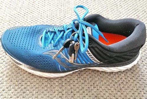 Blauer Laufschuh mit Schlüssel im Schnürsenkel eingebunden