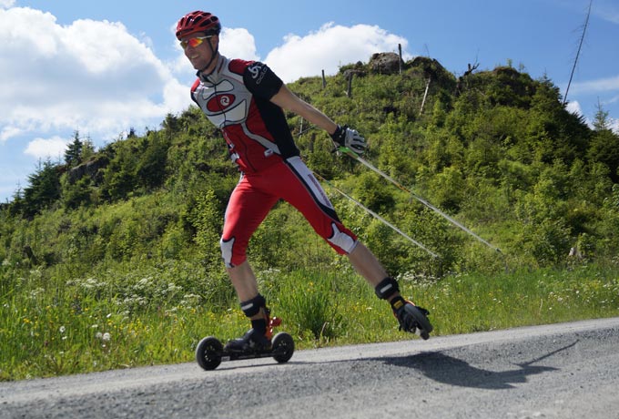 Mann der mit Skirollern auf einer Straße fährt