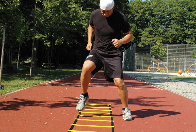 Sportler beim Agility-Training mit einer Koordinationsleiter.