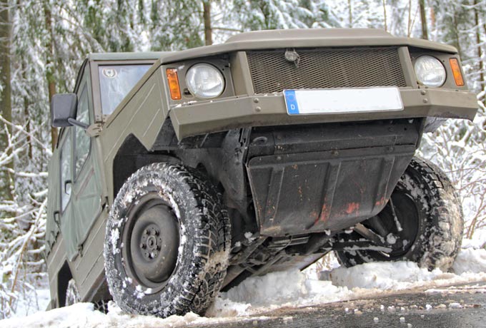 Olivfarbener VW Iltis fährt eine schneebedeckte Anhöhe hoch