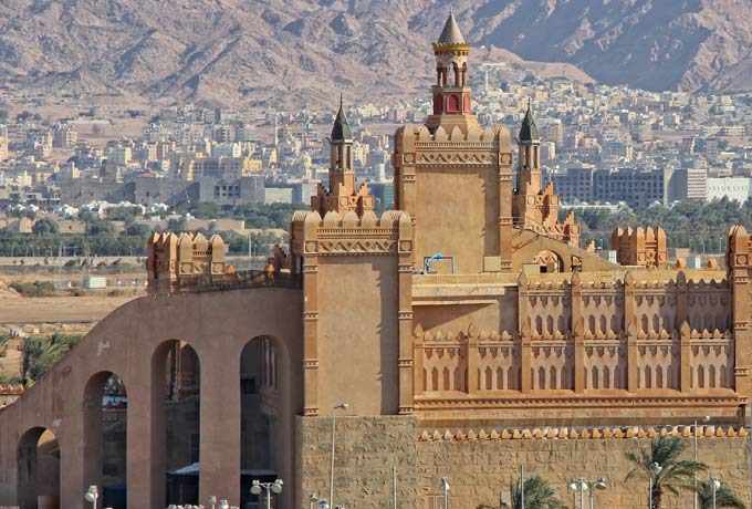 Schlossartiges Gebäude in der Stadt Eilat, im Hintergrund Berge