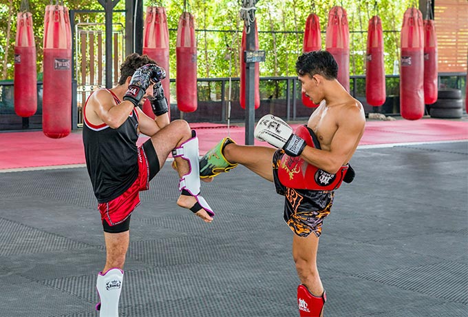 Zwei Thaiboxer beim Training, im Hintergrund rote Sandsäcke