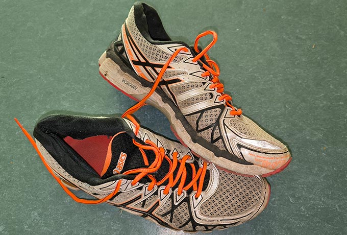 Ein paar weiße Laufschuhe von Asics mit orangen Schnürsenkeln